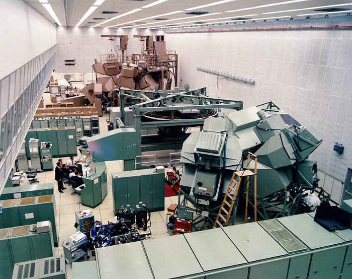 Colorized photo of men standing around a replica spacecraft, which was identical to the one flying high above the Earth’s surface.