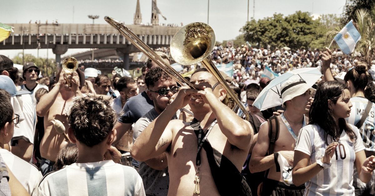 Lively street celebration in Buenos Aires with musical instruments and sports fans.