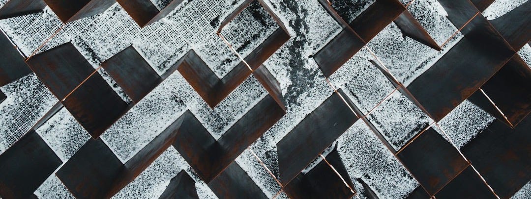 person in black pants walking on black and white concrete blocks