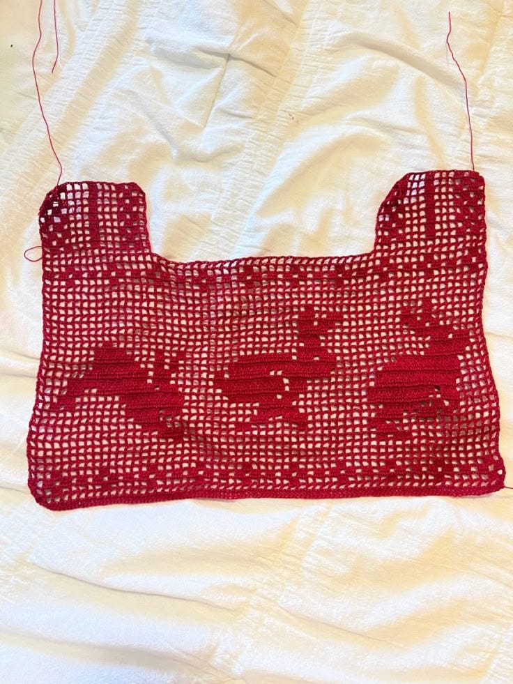 This may contain: a red piece of cloth on top of a white sheet with holes in the middle