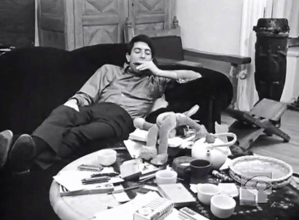 This may contain: a man sitting on a couch in front of a coffee table filled with clutter This may contain: a man sitting on a couch in front of a coffee table filled with clutter