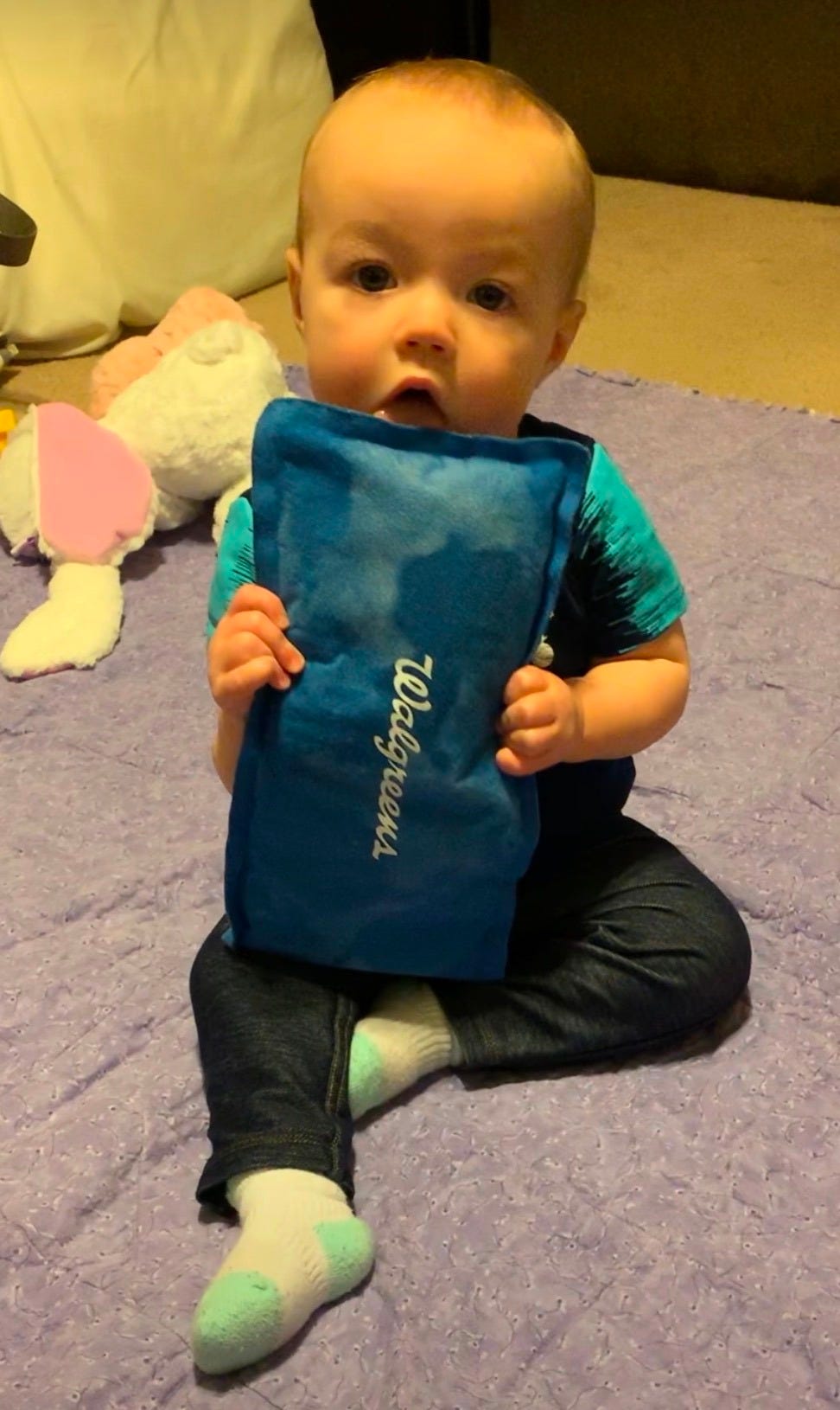 A photo of a baby holding a blue ice pack