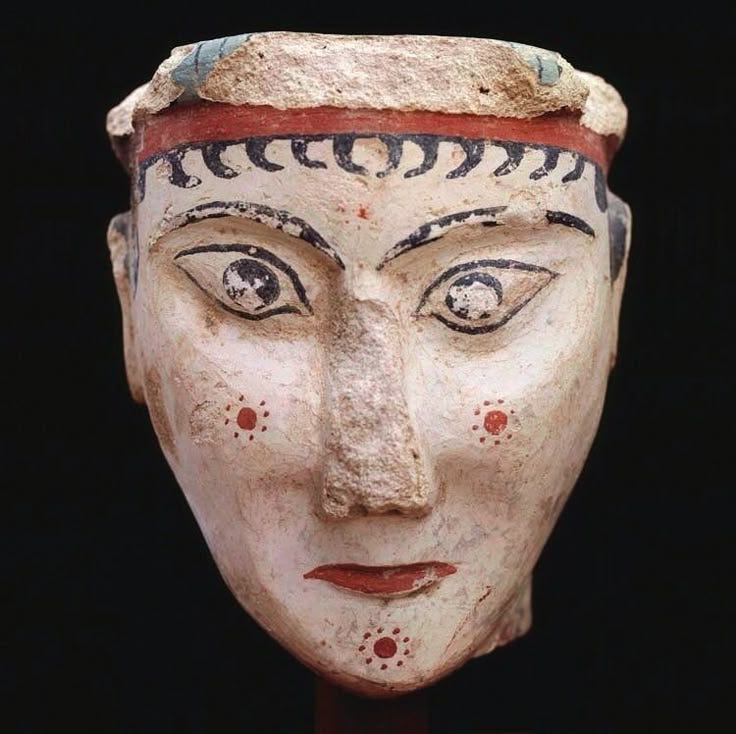 This may contain: an ancient mask is displayed on a black background with red and blue details around the face