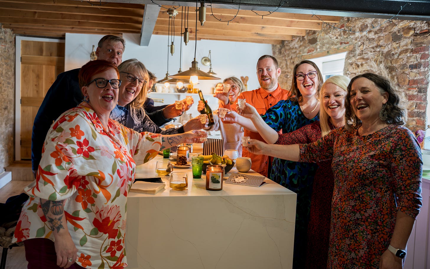 A group of people gathered in a kitchen raising a toast