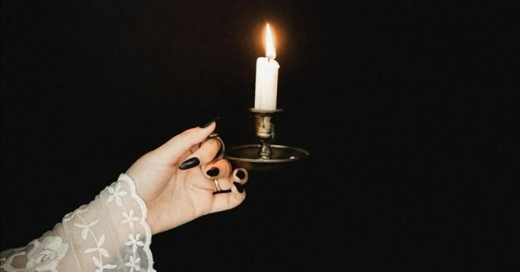 This may contain: a woman holding a lit candle in her hand