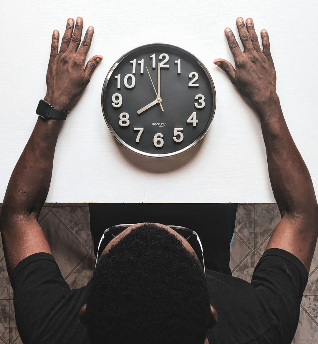 round black and white analog wall clock in front of man