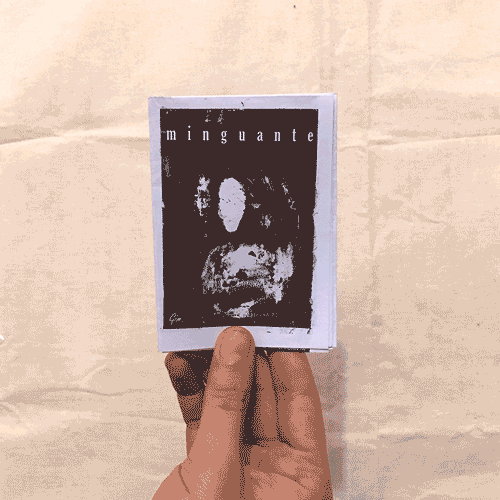 two hands leafing through the pages of a tiny black and white zine