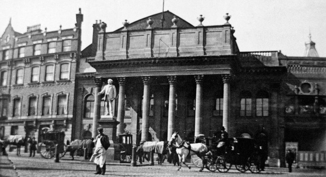 A black and white picture of the Theatre Royal in Nottingham with horse-drawn carts and people in front of it A black and white picture of the Theatre Royal in Nottingham with horse-drawn carts and people in front of it