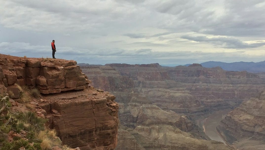 person standing near edge of rocky mountain person standing near edge of rocky mountain