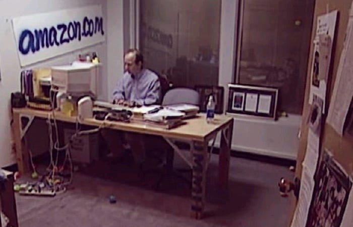 A photo of a man working in Amazon’s early office setup, illustrating how successful companies often begin in scrappy, chaotic environments where momentum matters more than polish.