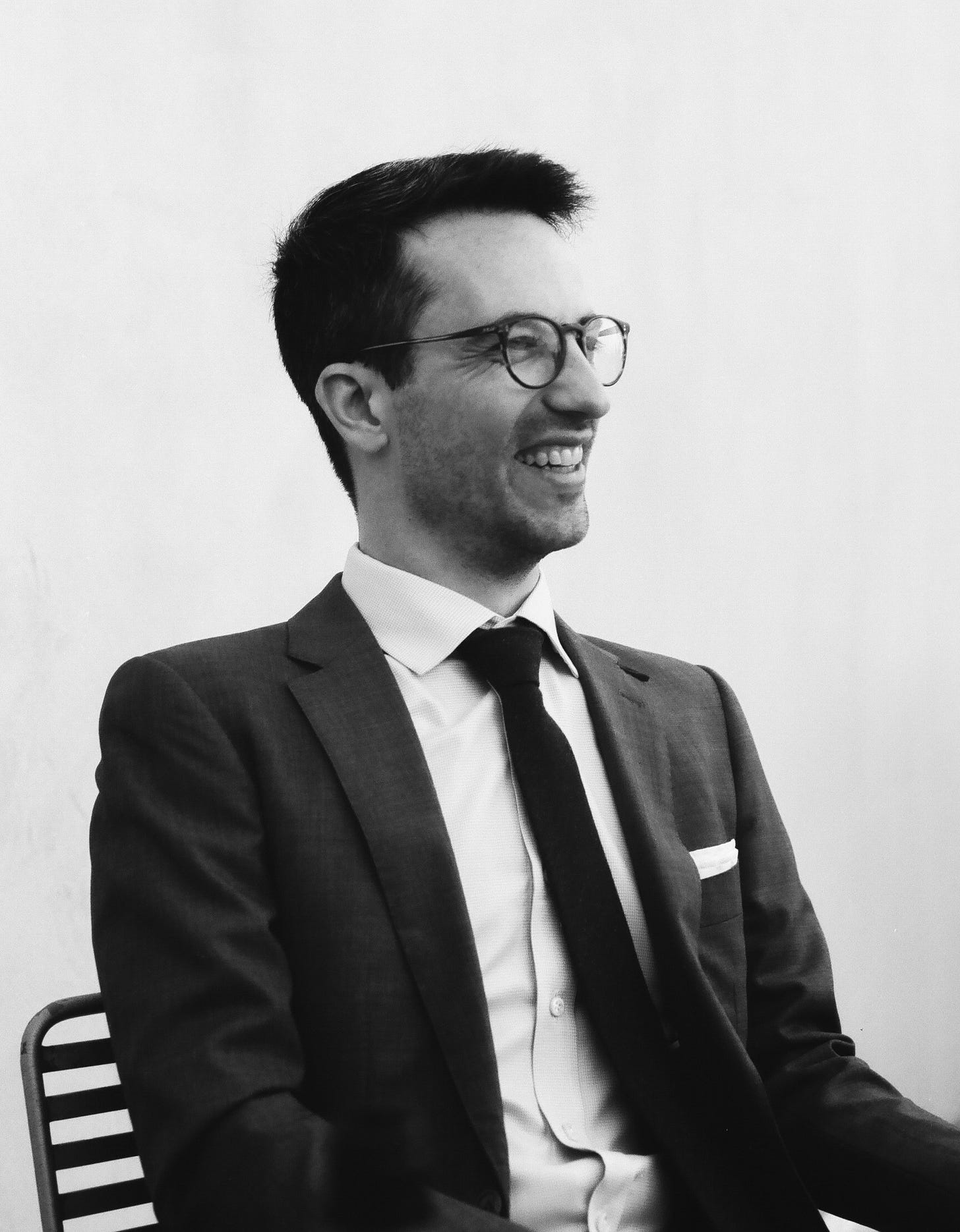 Simon Liebling in a black-and-white photograph seated in a suit