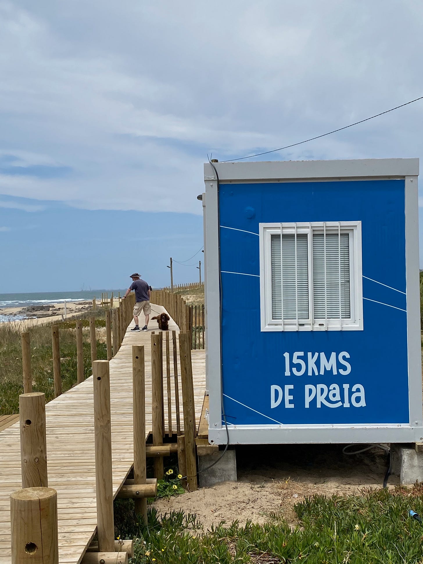Blue wall of changing block, '15km de praia'. Boardwalk on the left