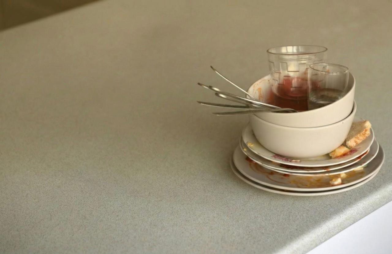 Vajilla y platos sucios sobre una mesada de cocina, imagen de portada para el artículo 'A pedir se aprende' de Carolina Garber sobre comunicación asertiva y vínculos laborales.