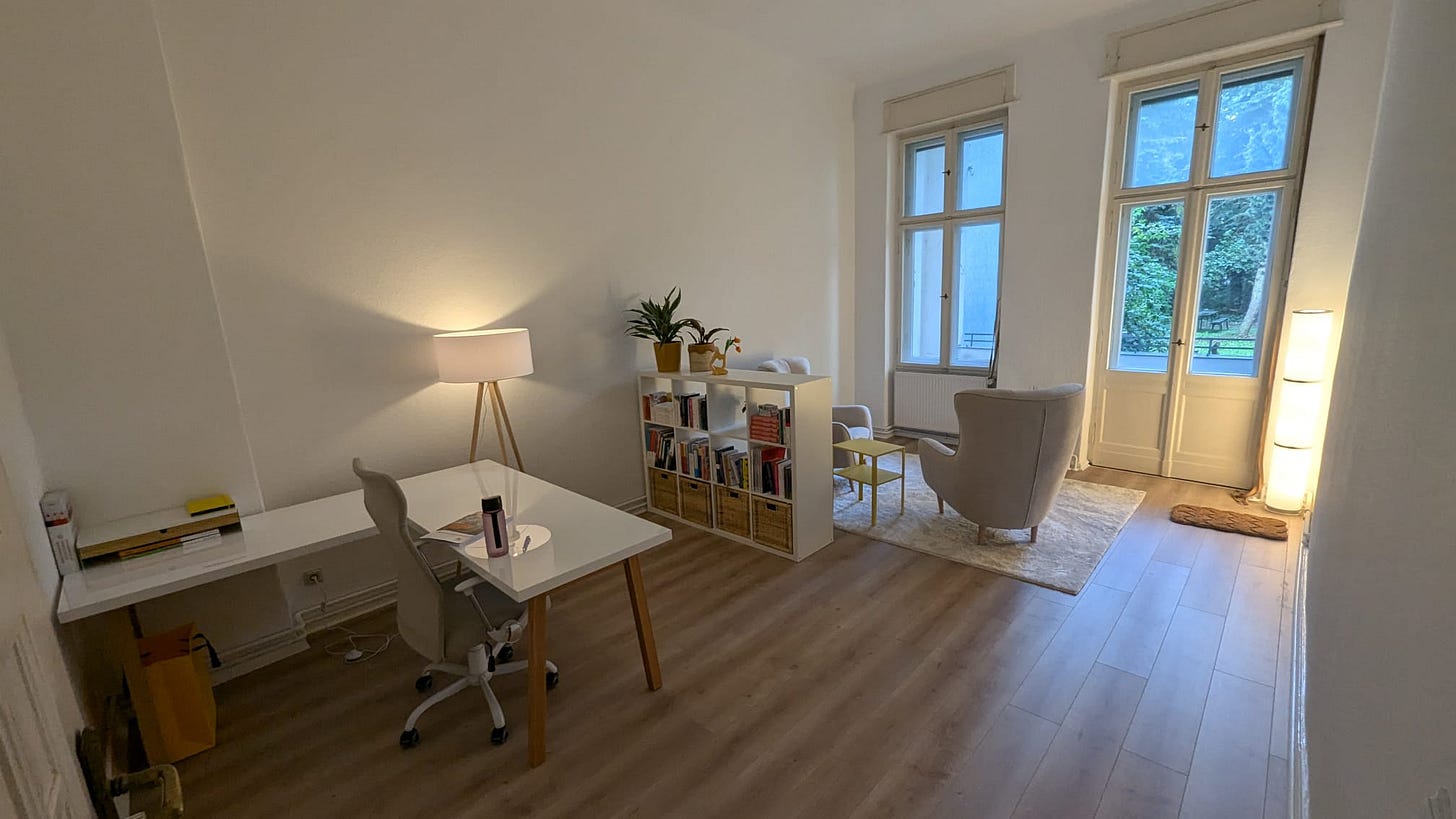 Mein neues Sprechzimmer, mit Schreibtisch, Blick in den Garten, Regal und Sesseln. 