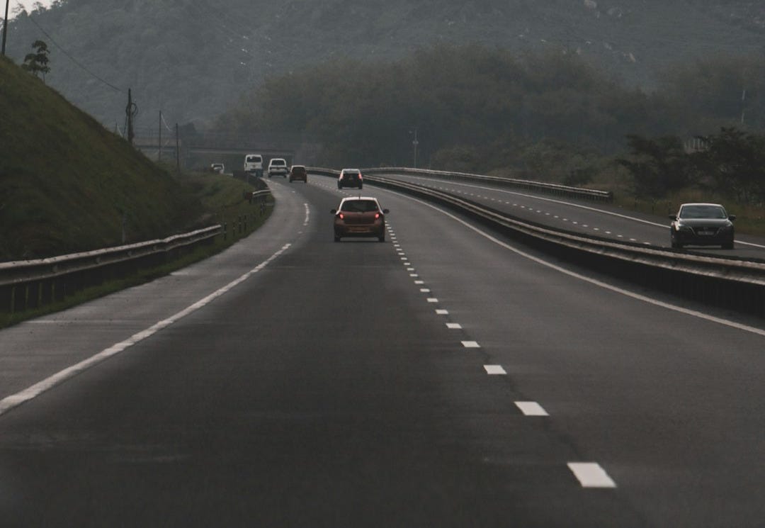 two cars driving down a road with a mountain in the background two cars driving down a road with a mountain in the background