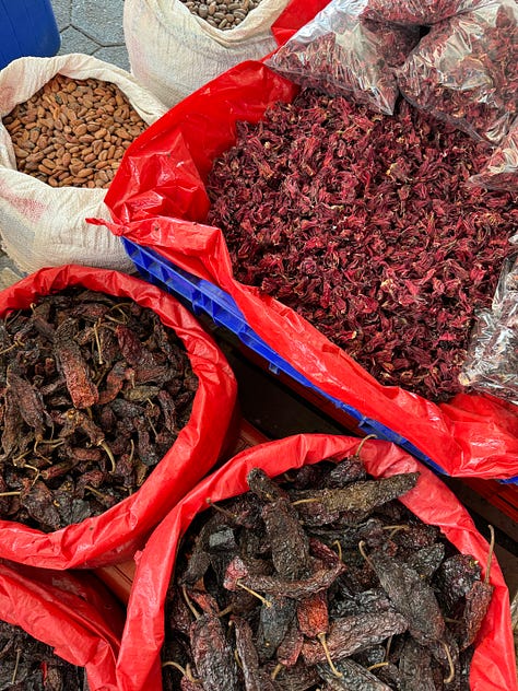 A nine image gallery showing dried chiles, coffee, cocoa beans, and sugar for sale at the market.