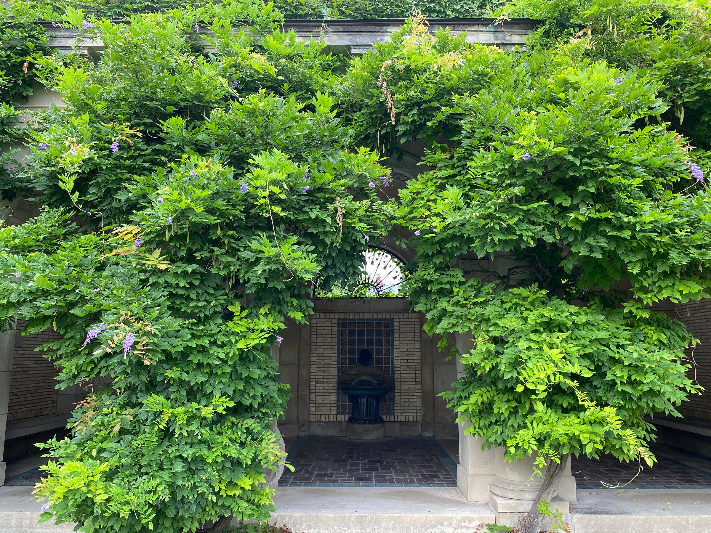 A Victorian-style patio with shrubbery in an archway before the entrance