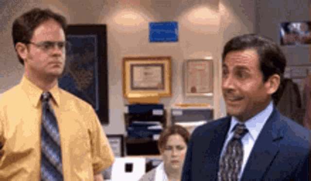 two men in suits and ties are standing next to each other in a room . two men in suits and ties are standing next to each other in a room .