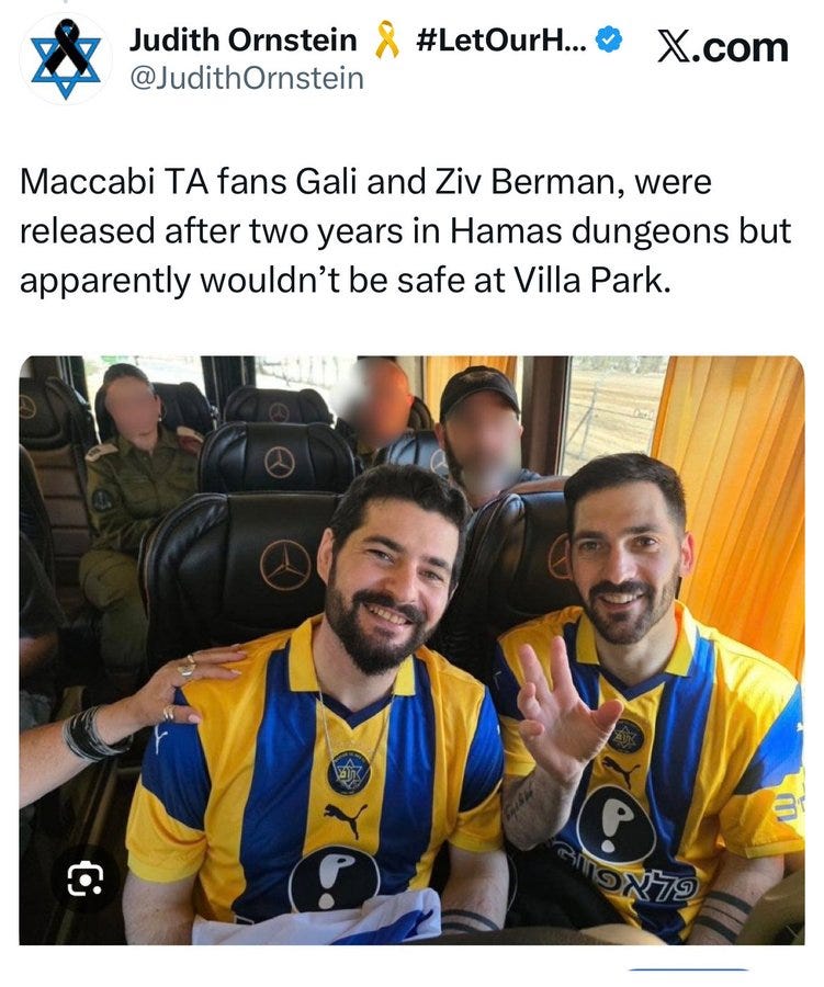 Bus interior with several blurred figures seated wearing hats and casual clothing, two men in foreground smiling and gesturing with hands raised, dressed in yellow and blue Maccabi TA soccer jerseys with Puma logos and sponsor patches, wristbands visible, window showing outdoor greenery.