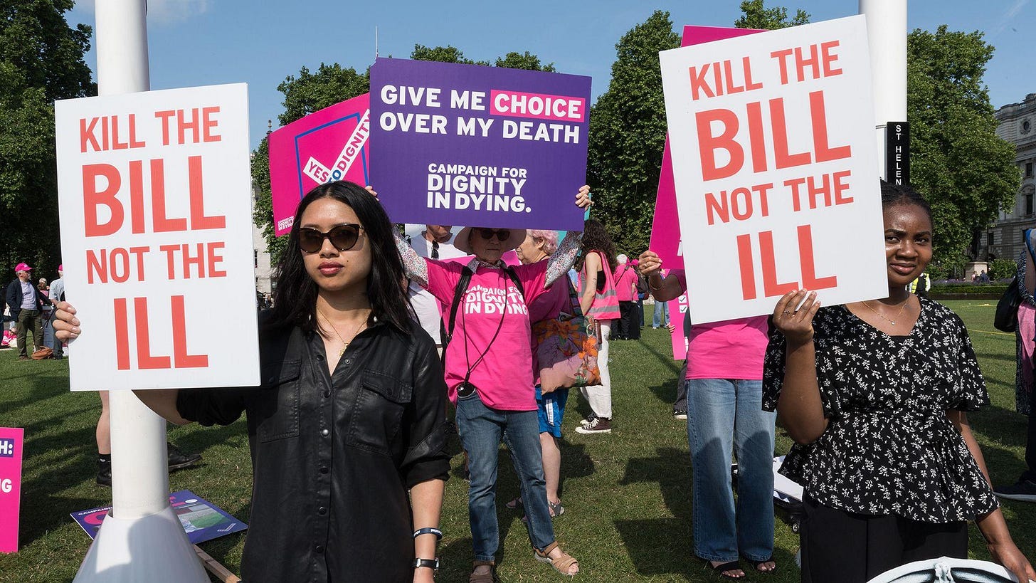 People holding signs saying 'kill the bill not the ill' and 'give me choice over my death' stand protesting outdoors in Parliament Square in early June 2025. People holding signs saying 'kill the bill not the ill' and 'give me choice over my death' stand protesting outdoors in Parliament Square in early June 2025.