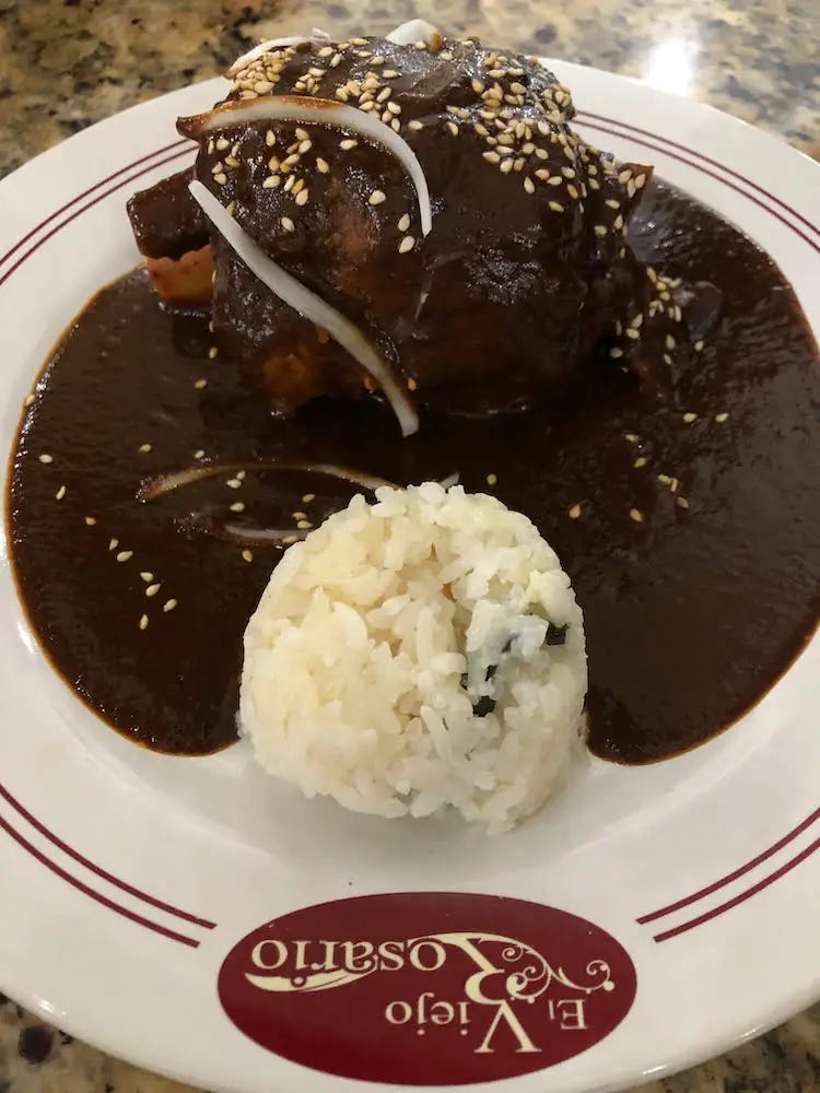 A lamb shank smothered in Mole Poblano alongside white rice