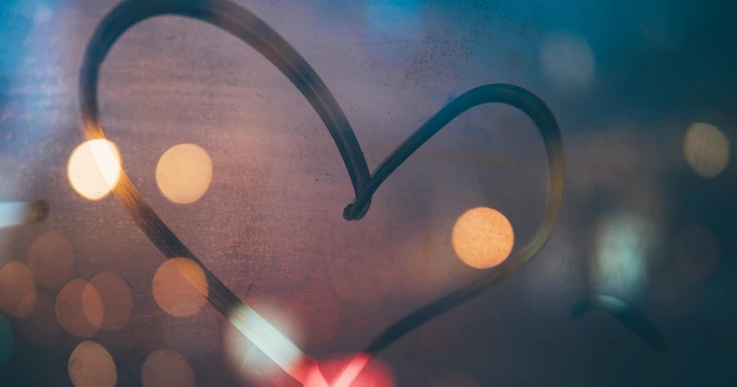 Heart-shaped outline made of bent iron with distant, out-of-focus lights in the background resembling glowing dots. Heart-shaped outline made of bent iron with distant, out-of-focus lights in the background resembling glowing dots.