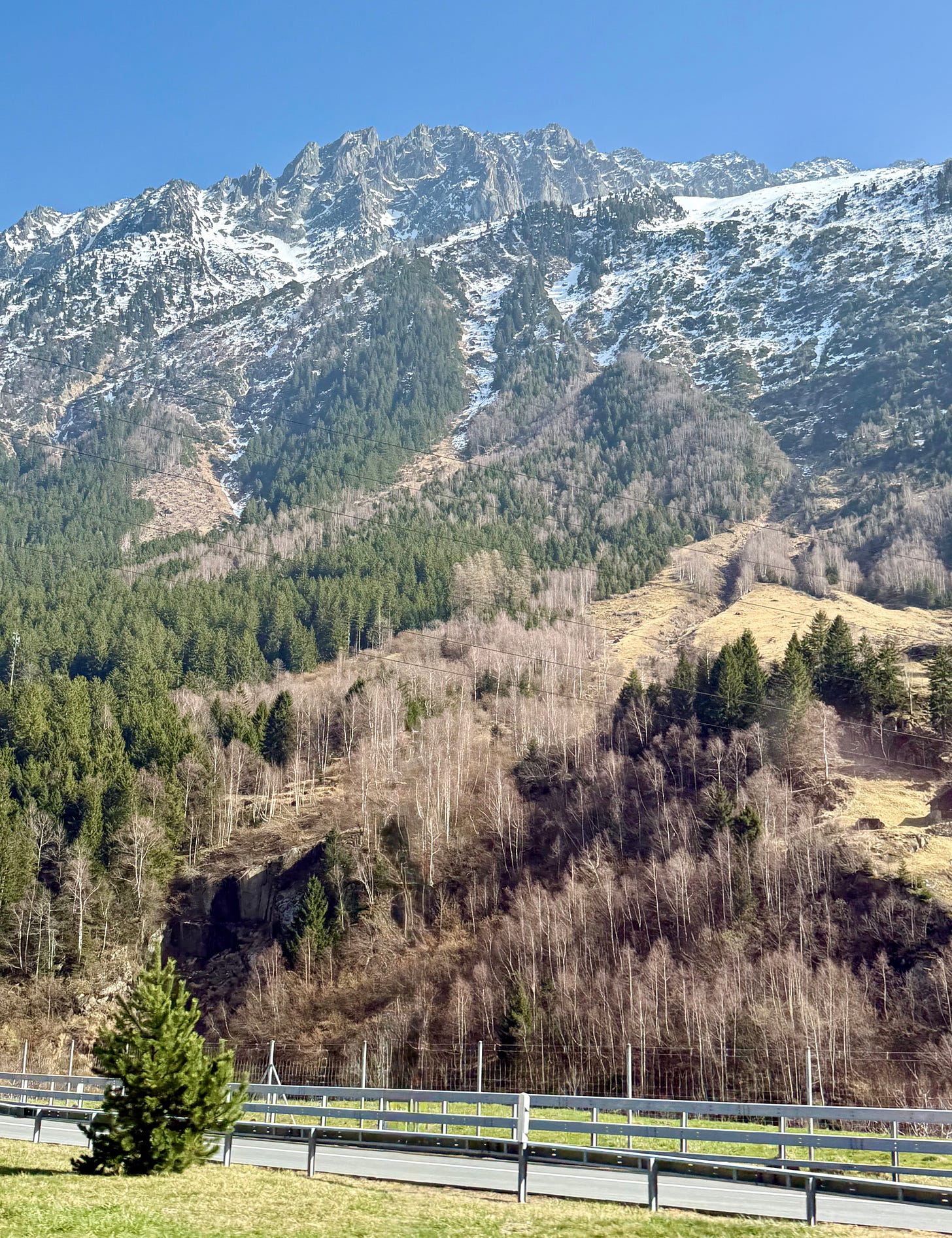 Mountain highway view - departure roForested ridges rising to snowy peaks Mountain highway view - departure roForested ridges rising to snowy peaks