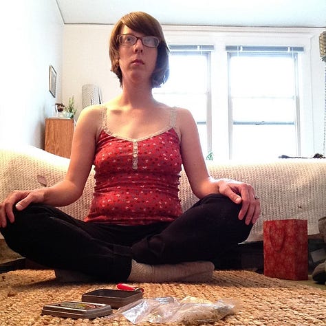 A person sitting cross legged, a sidewalk with strewn flower petals, a glass of beer.