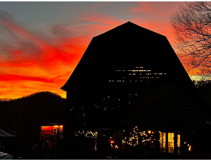A photo of a grief altar set in the corner near the barn with the words 'appalachia strong' written on a piece of wood, flowers and candles and notes surround it. The 2nd photo is the silouhette of the barn against a blazing orange and red sunset.