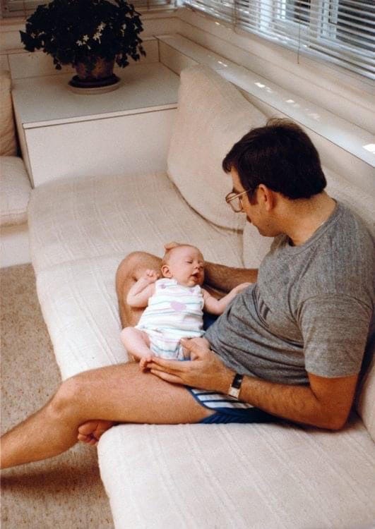 Photo of a man on a beige couch holding a baby