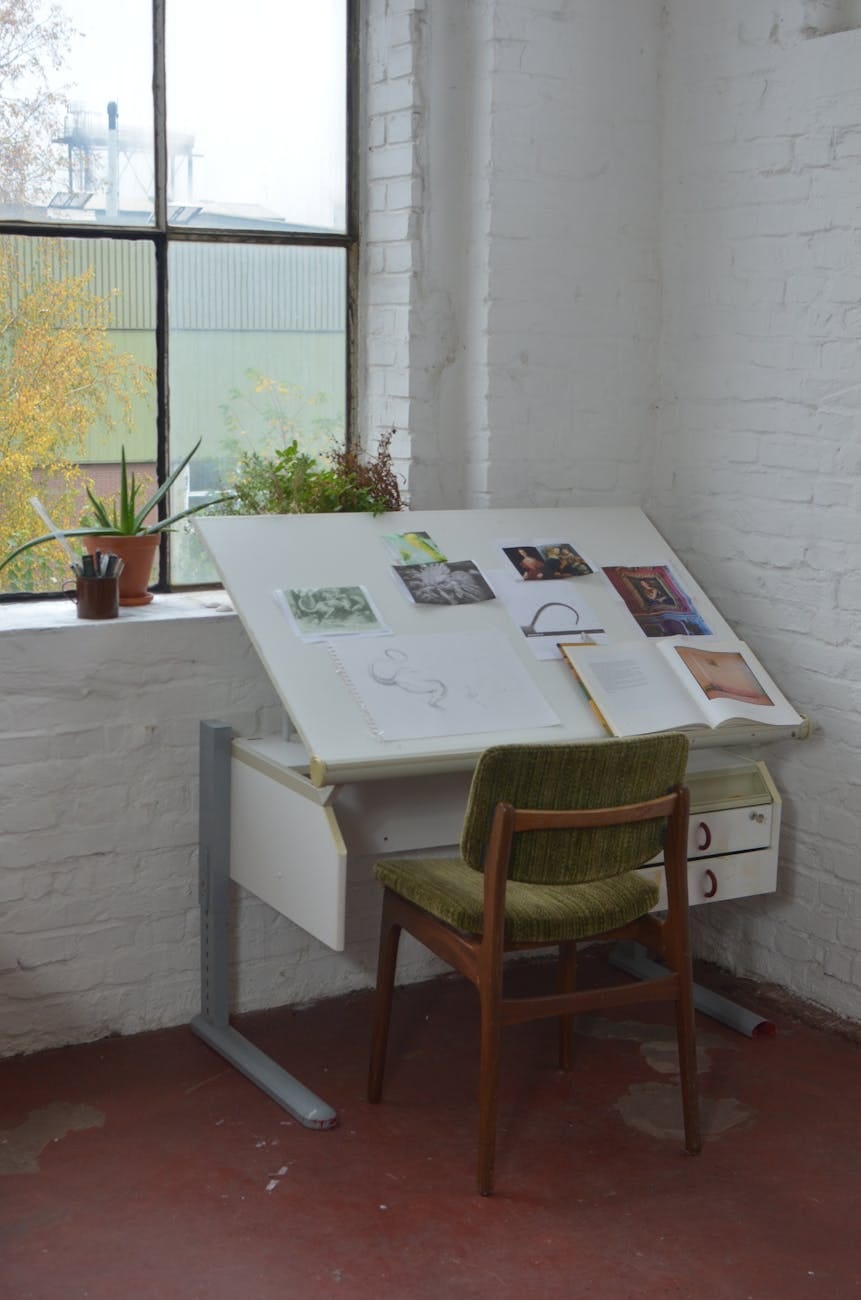 chair placed near window and table with drawings chair placed near window and table with drawings