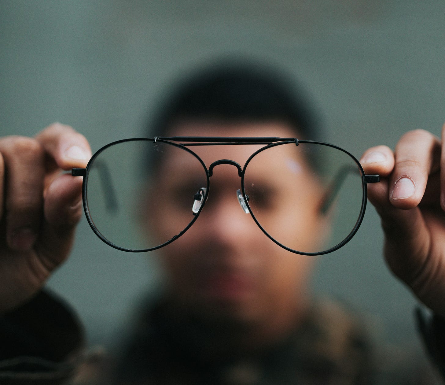 A man holding a pair of clear glasses to sharpen vision