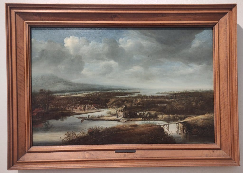 A painting of a Dutch river, meandering through the landscape with a bridge in the foreground and a town in the middle, while a mountain rises at the back of the scene.