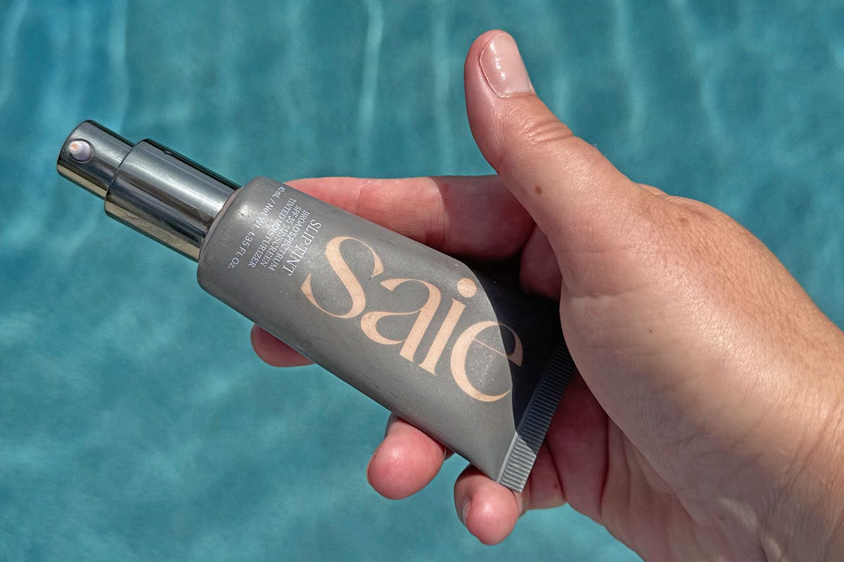 Female hand holding Saie tinted moisturizer with SPF Female hand holding Saie tinted moisturizer with SPF