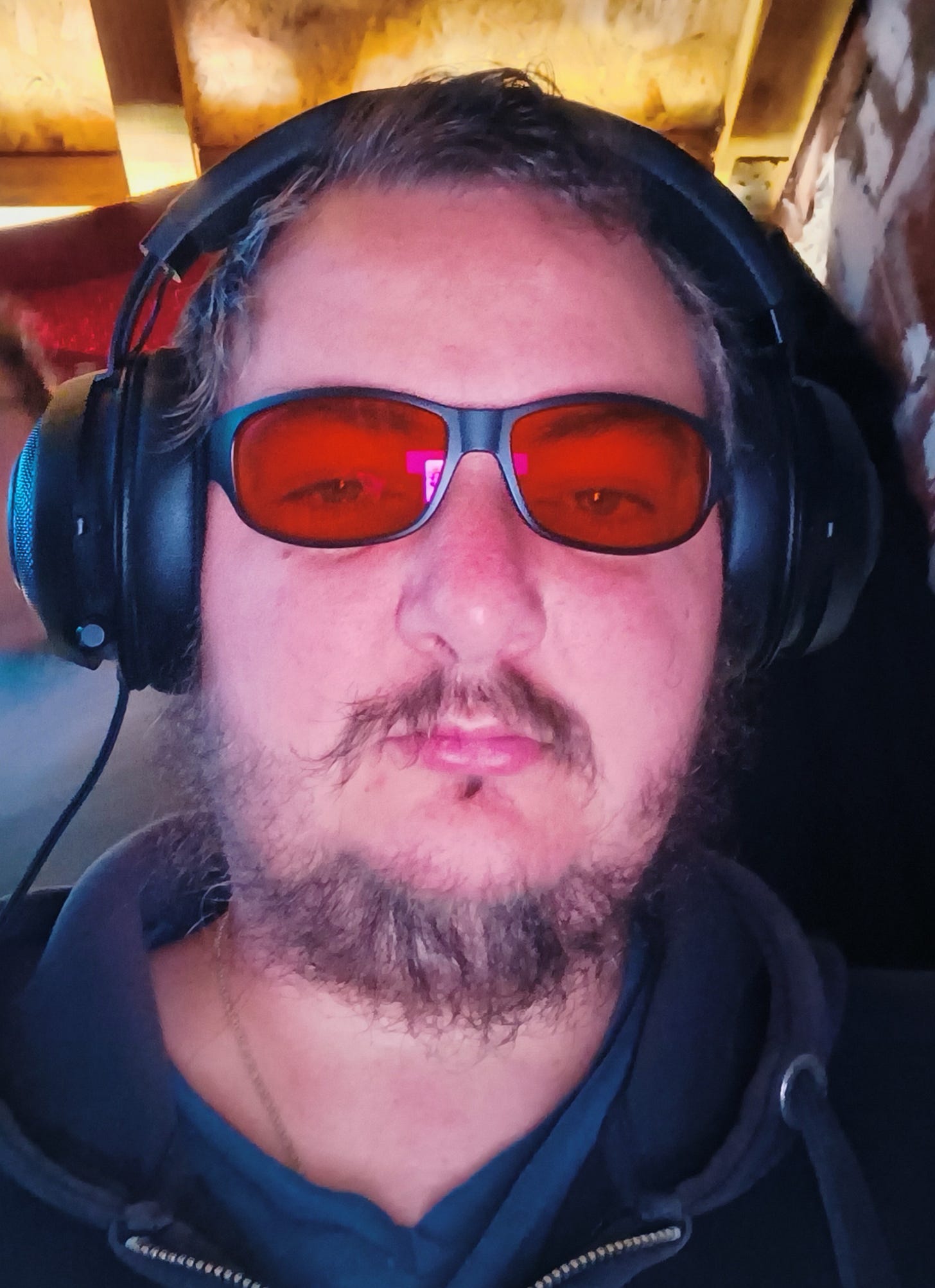 Photo of author with red glasses and headphones on