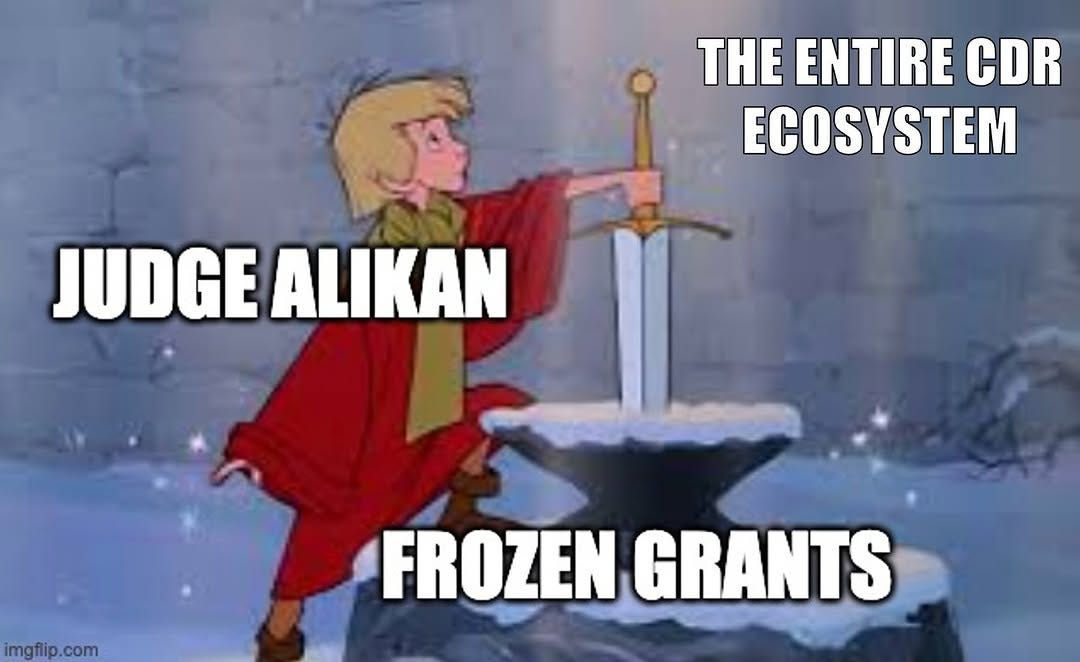 Arthur pulling the sword from the stone in Disney's The Sword in the Stone. Arthur is labelled "Judge Alikan", the stone "Frozen grants", and the onlookers "The entire CDR ecosystem".