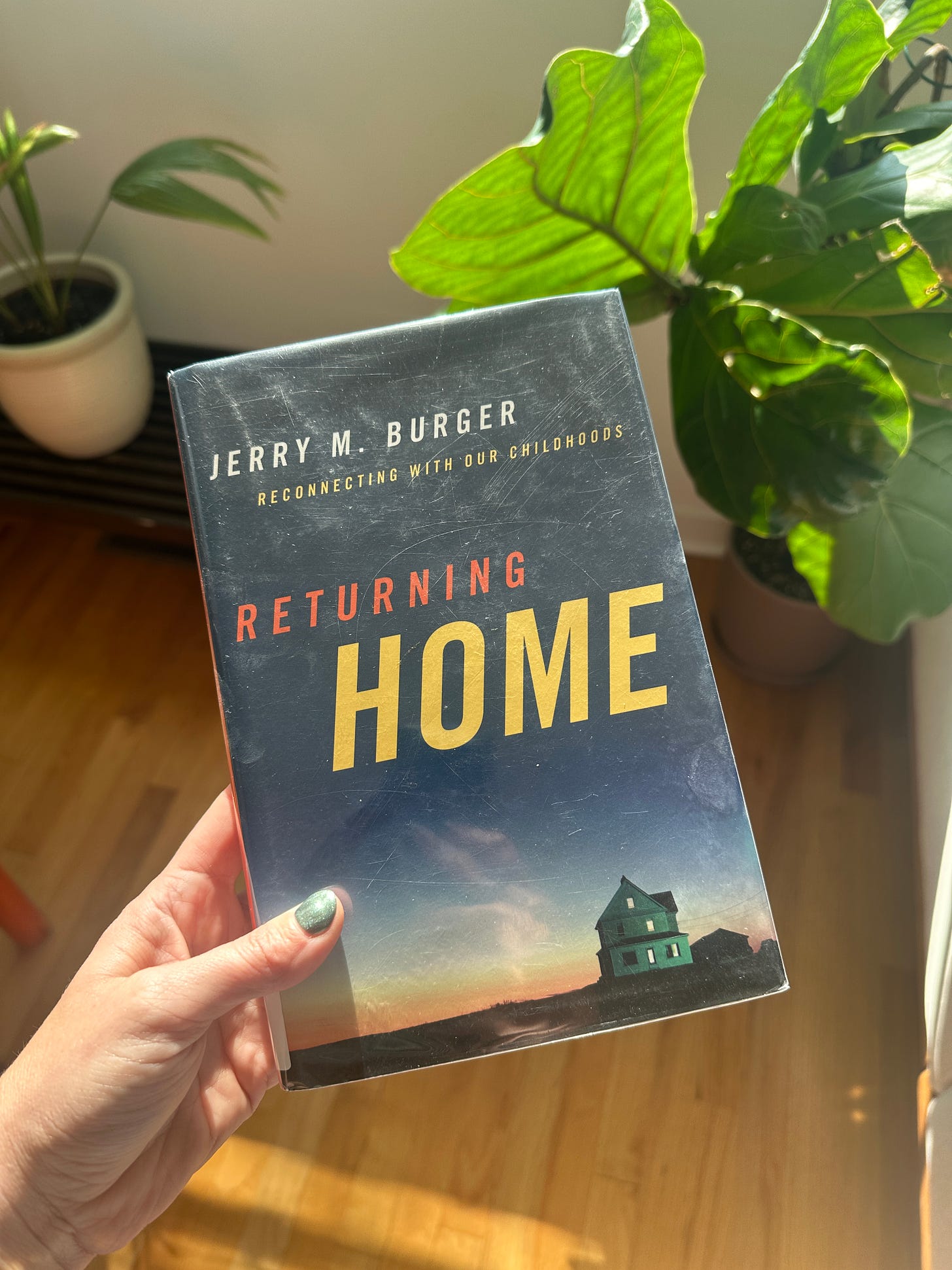 "Returning Home: Reconnecting with Our Childhoods" by Jerry M. Burger. The cover of the book features a house on a hill at sunset.