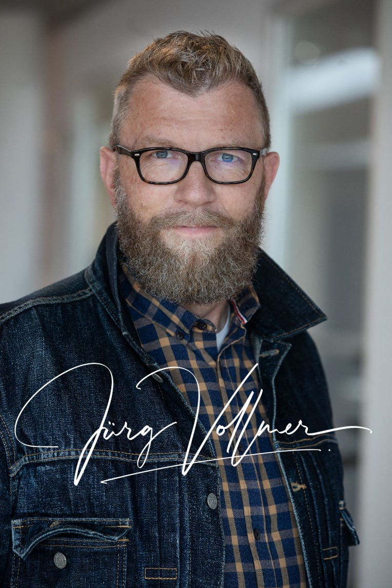 Der Agrarjournalist Jürg Vollmer mit Bart und schwarzer Brille, blau kariertem Hemd und Jeansjacke. Über der Jackee steht in weisser Handschrift die Signatur «Jürg Vollmer». Der Agrarjournalist Jürg Vollmer mit Bart und schwarzer Brille, blau kariertem Hemd und Jeansjacke. Über der Jackee steht in weisser Handschrift die Signatur «Jürg Vollmer».