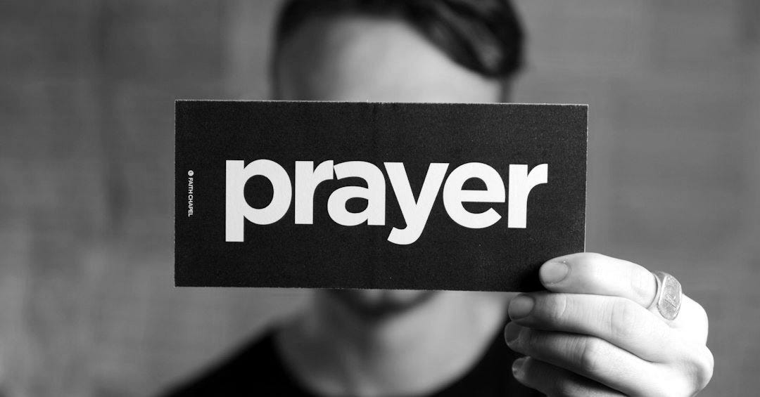 a man holding up a sign that says prayer