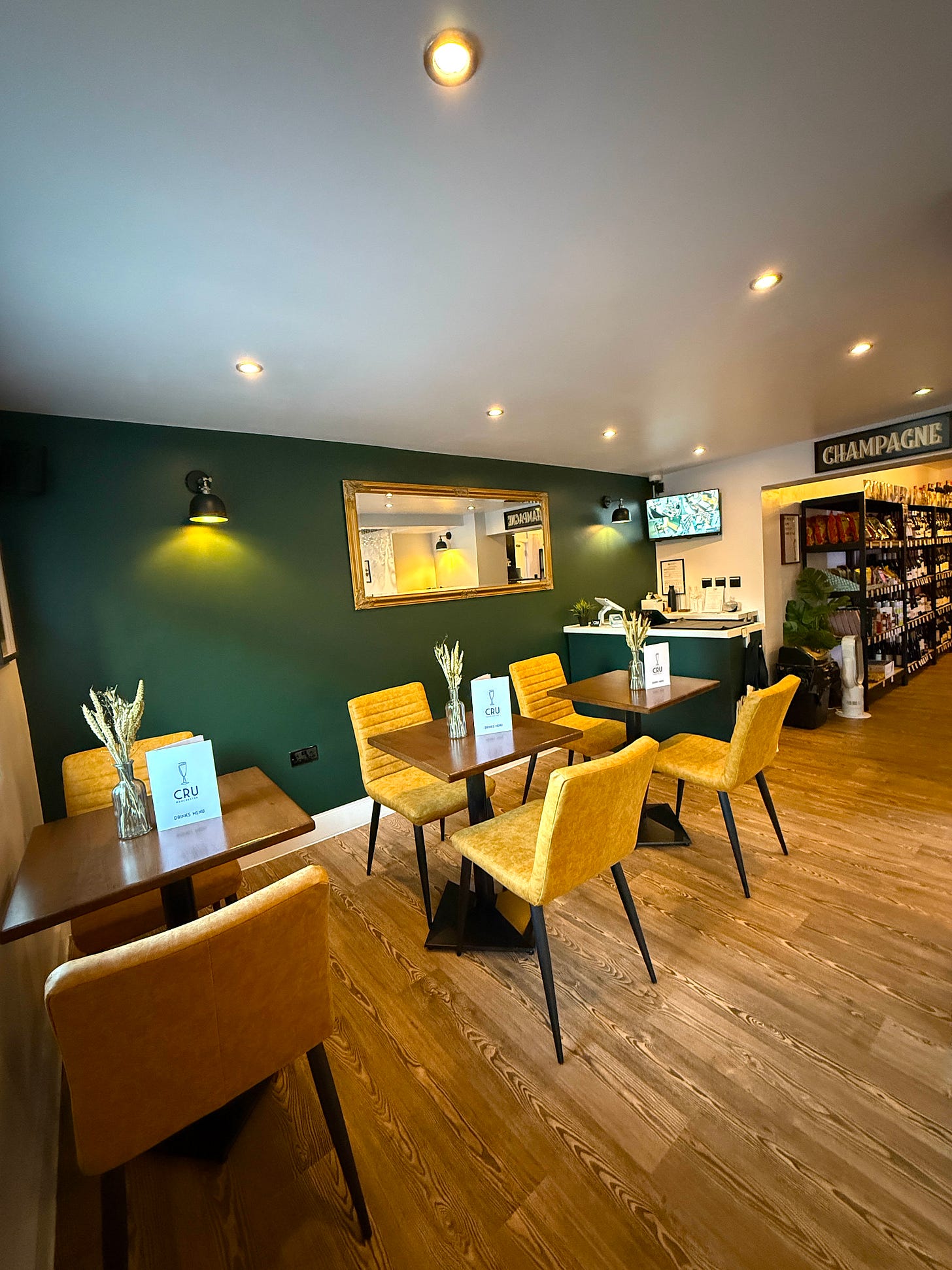 the interior of wine bar Cru didsbury with dark green walls and yellow seats