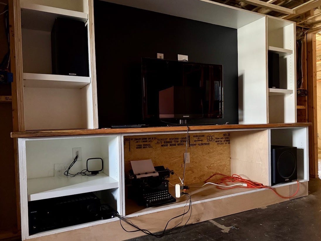 An almost-completed entertainment center with av equipment placed in cubbies.