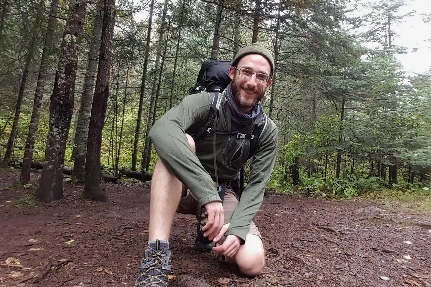 Alex Pretti takes a knee for a portrait on a forested hiking trail.