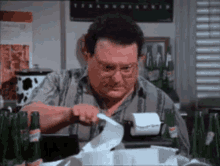 a man is sitting at a table with bottles of beer and a receipt on a printer . a man is sitting at a table with bottles of beer and a receipt on a printer .