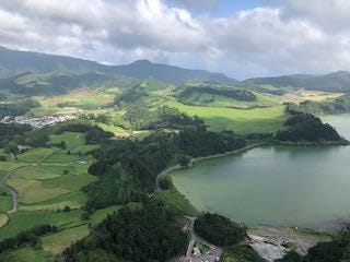 Photos of a sweeping view of an island with an emerald green lake, a plaza in Punta Delgada with a white chuch and white buildings trimmed in brown, a plant-filled tunnel going into a cave.