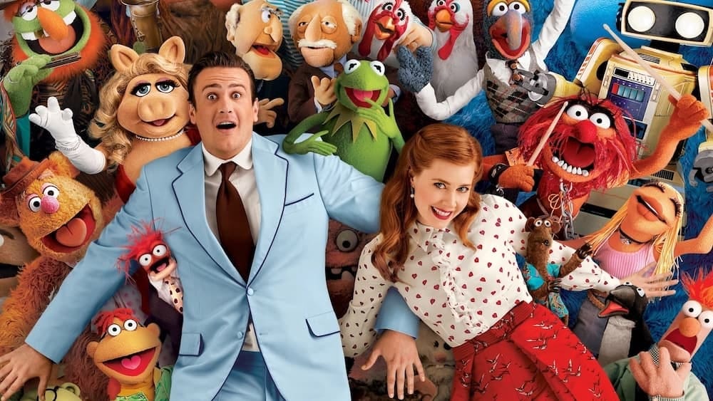 Jason Segel and Amy Adams surrounded by all of the Muppets