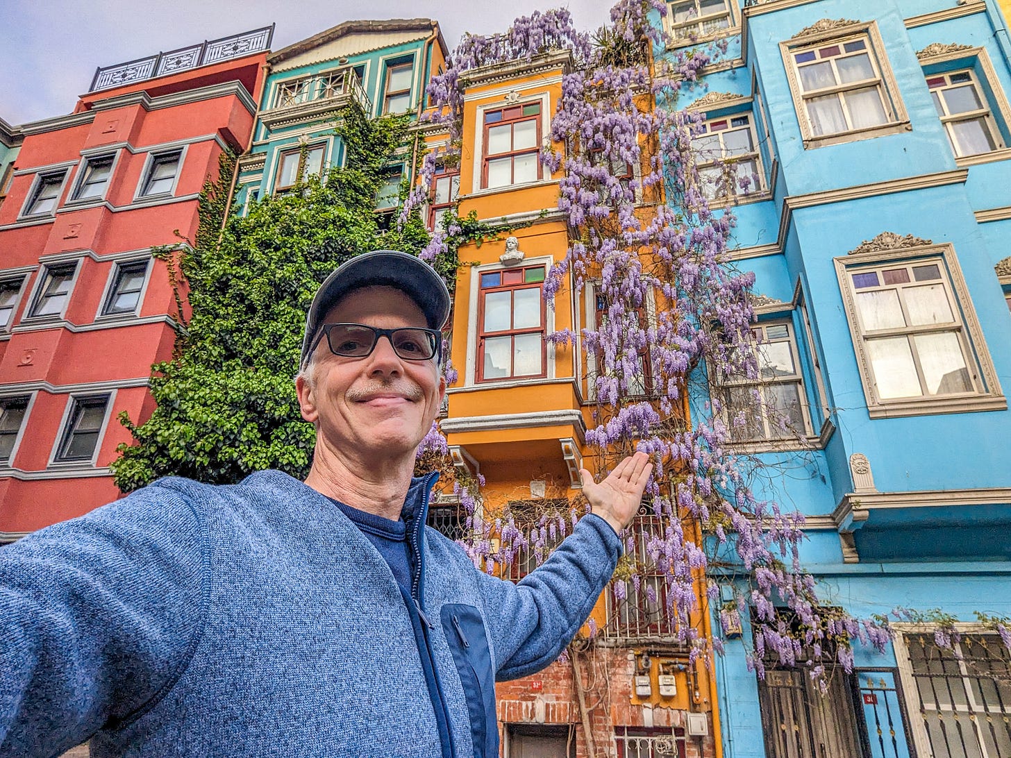 Michael standing in front of buildings painted green, blue, yellow, and orange. 