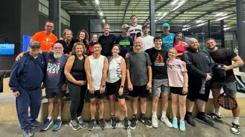 Sebastian Cunliffe A large diverse group of people smiling at the camera at the Rocket Padel indoor centre. They are all dressed in sports gear and some are posing with rackets. Sebastian Cunliffe A large diverse group of people smiling at the camera at the Rocket Padel indoor centre. They are all dressed in sports gear and some are posing with rackets.