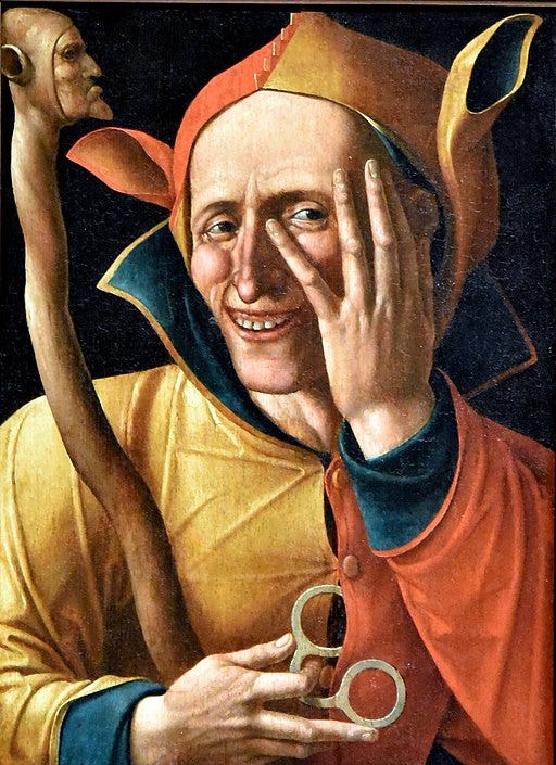 Jester peaking through his hands smiling wrily