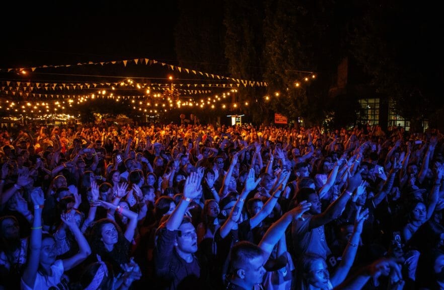 A crowd of people wave their hands.