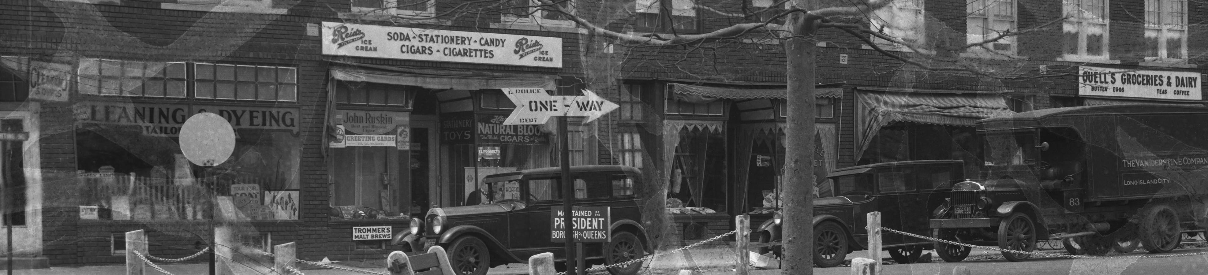 Image is a photograph of the west side of Whiting Square. There are four storefronts, including a cleaner/tailor, a store selling candy, soda, cigars, and more, as well as meat and other markets. Image is a photograph of the west side of Whiting Square. There are four storefronts, including a cleaner/tailor, a store selling candy, soda, cigars, and more, as well as meat and other markets.